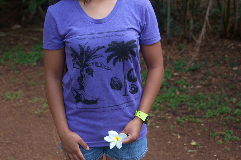 Purple screen print t-shirt on female model holding plumeria.