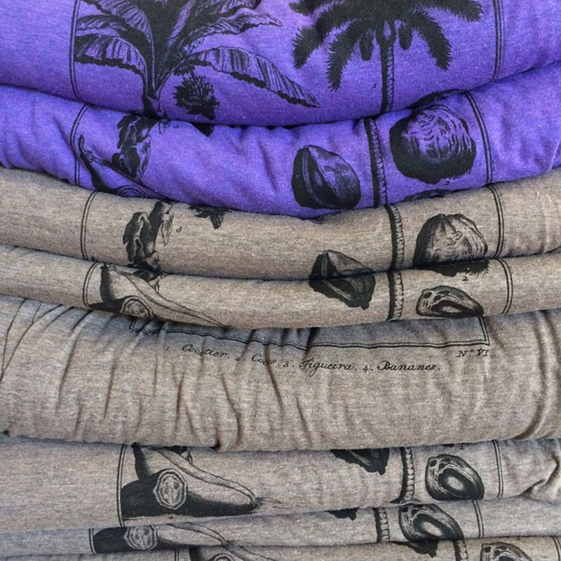 A stack of folded t-shirts, purple on top and brown on bottom.